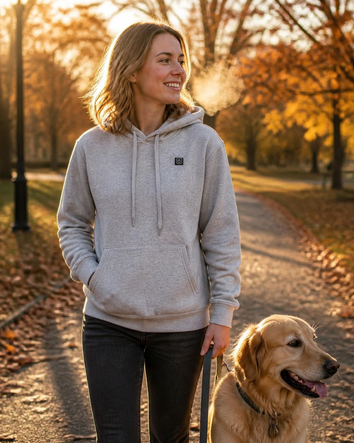 Frau im grauen ArticLux Wärmenden Hoodie beim Herbstspaziergang mit Hund