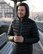 Mann mit Kapuze in der beheizbaren ArticLux Steppjacke am Bahnsteig