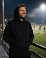 Mann im schwarzen ArticLux Wärmenden Hoodie abends am Fußballplatz