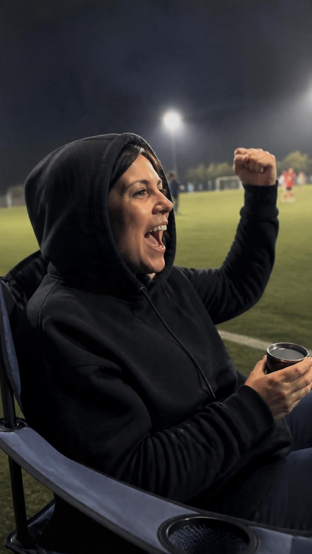 Frau im schwarzen ArticLux Hoodie jubelt am Spielfeldrand