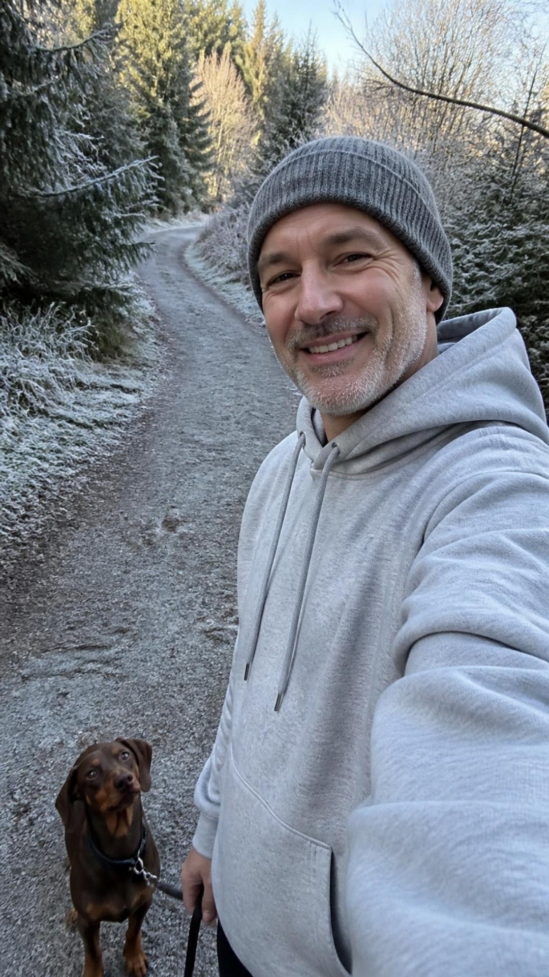 Selfie im grauen ArticLux Hoodie mit Dackel im Wald